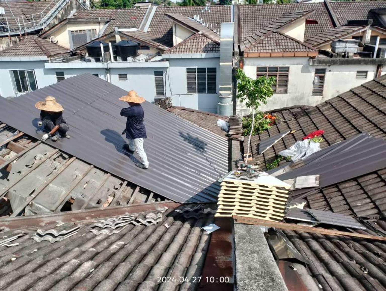 Metal roof sheet installation and replacement work in progress.